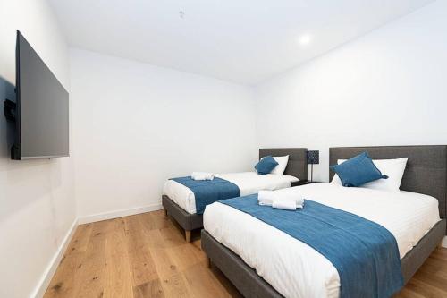 墨尔本Calming Urban Oasis的一间卧室配有两张床和一台平面电视