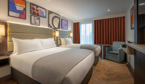 伦敦Maldron Hotel Finsbury Park, London的酒店客房,配有两张床和椅子
