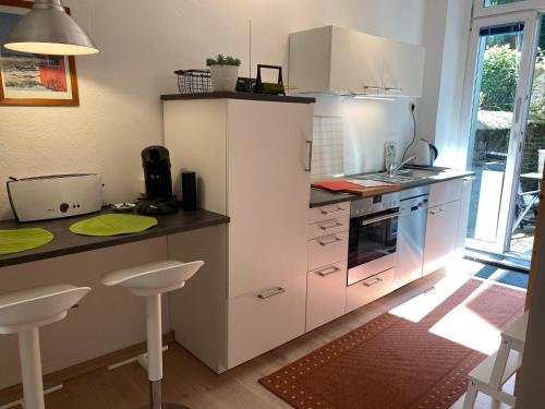 伍珀塔尔Gehen & Fahrrad Elberfeld的厨房配有白色橱柜和带凳子的台面