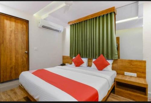 艾哈迈达巴德HOTEL SAFARI INN的一间卧室配有一张带红色枕头的大床