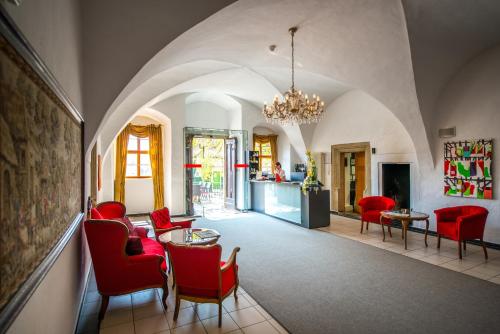 奥尔施泰特奥尔施泰特城堡度假酒店的客厅配有红色椅子和桌子