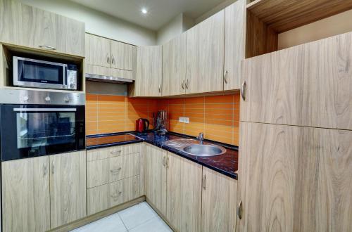 塞格德Egyetem Apartman的厨房配有木制橱柜、水槽和微波炉