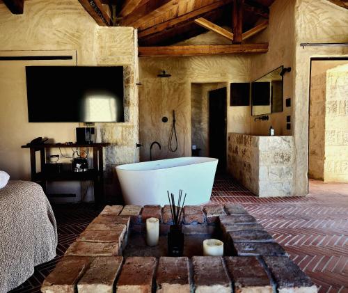 罗希姆诺Amalen Suites Adults Only的带浴缸、电视和床的浴室。