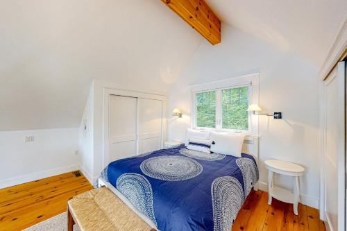 WestportPeriwinkle Cottage的一间设有蓝色床的卧室,位于一个设有窗户的房间