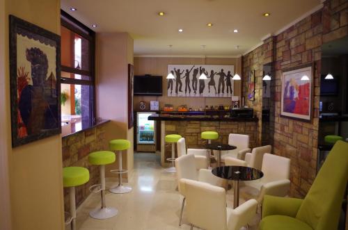 雅典Hotel Exarchion的餐厅设有酒吧,配有绿色的桌椅