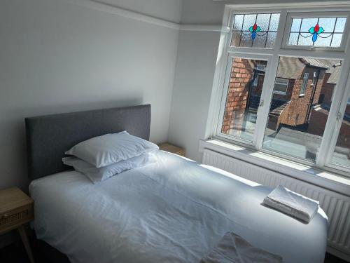 雷德卡Sandringham House的卧室内的一张白色床,设有窗户
