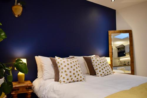 克罗伊登Stylish centrally-located studio with parking的一间卧室设有蓝色的墙壁和一张带枕头的床。