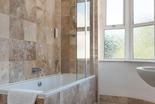 北安普敦普劳酒店 的带浴缸、水槽和窗户的浴室