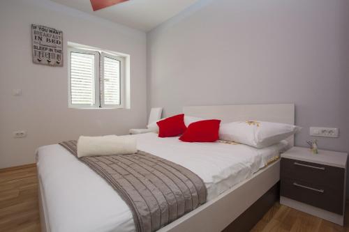 马卡尔斯卡劳拉公寓的卧室配有带红色枕头的白色床