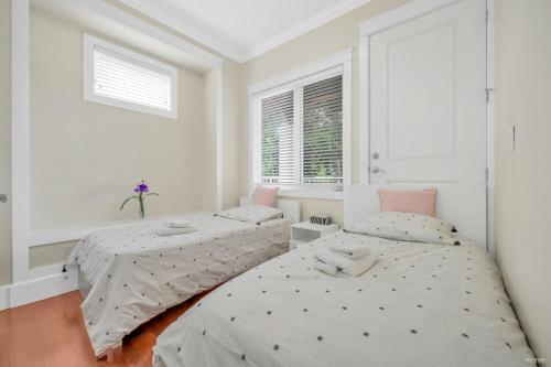 温哥华Luxurious Getaway in Vancouver-Private room with attached bathroom的卧室设有两张床,拥有白色的墙壁和窗户。