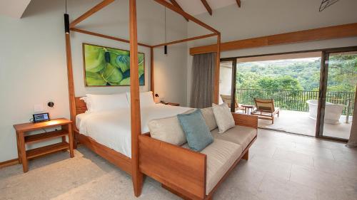 福尔图纳塔巴康温泉Spa度假村的一间卧室配有一张天蓬床、一张沙发和一个阳台