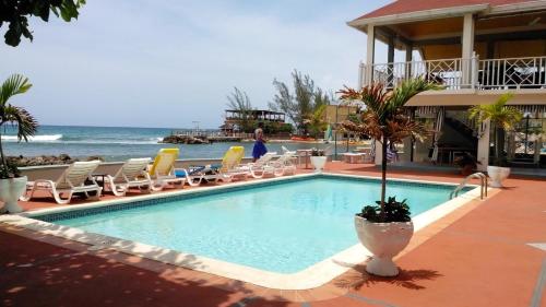 拉纳韦贝派珀度假酒店的一个带椅子的游泳池,背景是大海
