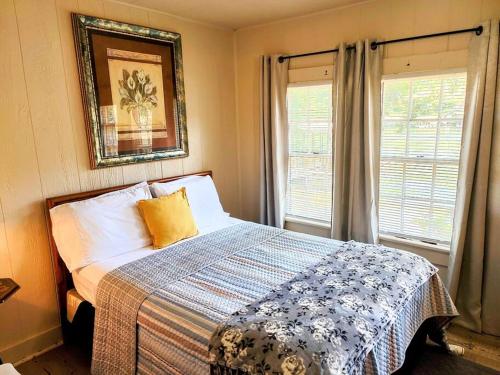 温泉城#04-Adorable Large 1 Bedroom Lakeside Cottage- Pet Friendly的一间卧室配有一张带毯子的床和两个窗户
