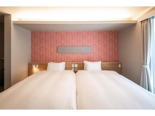 静冈Hotel Celeste Shizuoka Takajo - Vacation STAY 94099v的红色墙壁的客房内的两张床