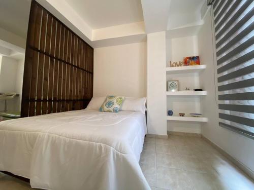 卡利APARTAESTUDIO EN SAN FERNANDO的卧室配有白色的床和窗户。