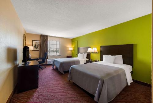 伍德森特瑞斯机场品质酒店的酒店客房设有两张床和绿色的墙壁。