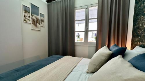 阿德耶Costa Adeje - Amazing Ocean And Teide View - Fast WiFi, Air Con的一间卧室配有一张带蓝色枕头的床和一扇窗户。