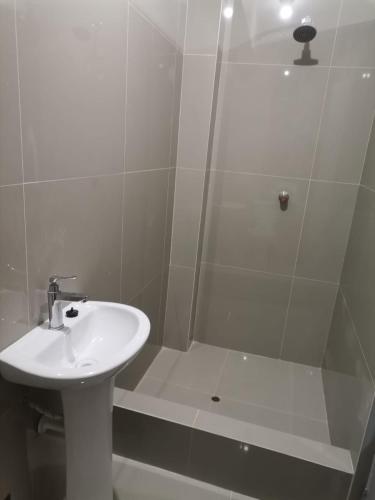 普卡尔帕Hotel JK的白色的浴室设有水槽和淋浴。