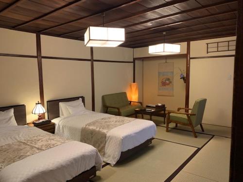仓敷吉井日式旅馆的一间卧室配有两张床、一把椅子和一张书桌