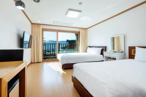 西归浦市The Bay Jeju Resort的酒店客房设有两张床和一个阳台。