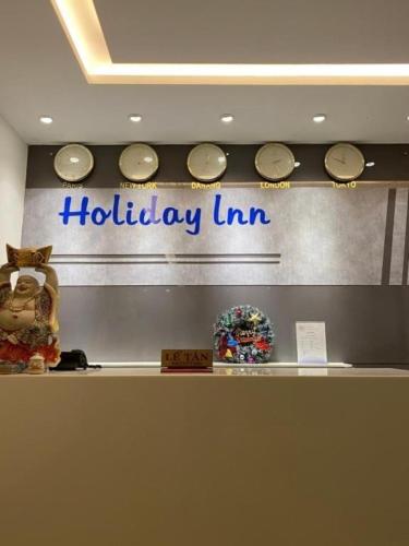 岘港Holiday Inn Hotel的墙上的假日旅馆标志,带时钟