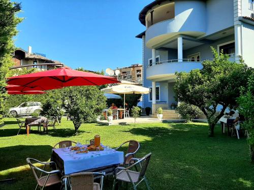 培拉特Hotel Vila Arbri的院子里的桌子上摆放着红色的雨伞和椅子