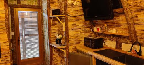 萨尔拉拉卡内达La cabane des amoureux的厨房设有木墙、微波炉和电视。