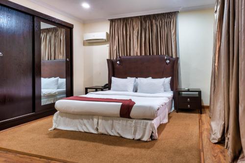拉各斯宾至如归宾馆的一间卧室配有一张大床和木制床头板