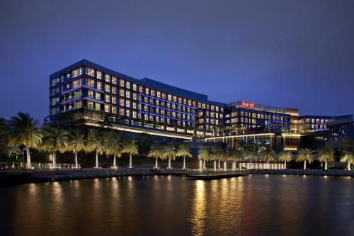 深圳深圳欢乐海岸万豪行政公寓的水体前有棕榈树的建筑