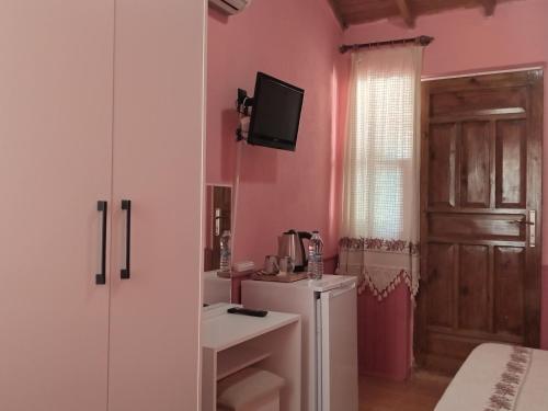 阿德拉桑Akya Adrasan Pansiyon的浴室设有粉红色的墙壁、水槽和冰箱。