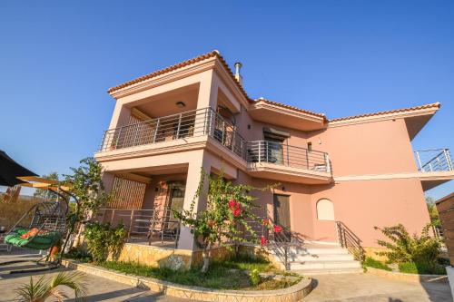 AmbelókipoiNektarios & Eftychia Suites的粉红色的房子,设有阳台和鲜花