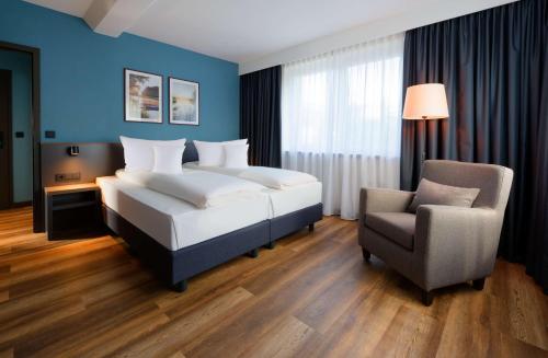 不莱梅ATLANTIC Hotel Landgut Horn的配有一张床和一把椅子的酒店客房