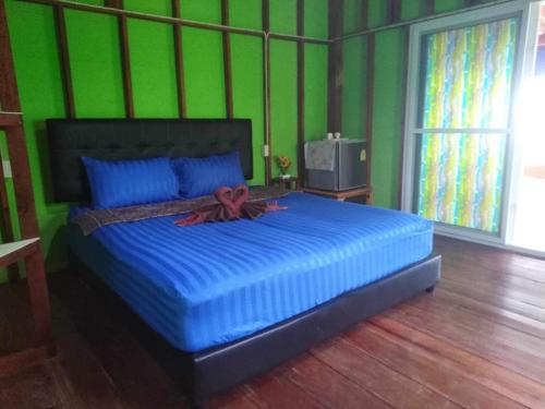 董里Koh Mook Rem Ley的一间卧室配有一张大床、蓝色枕头和绿色墙壁。
