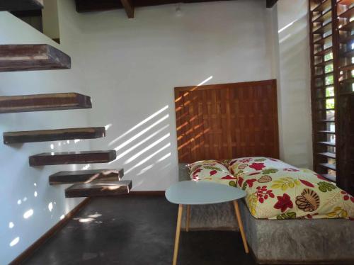 阿姆巴托洛阿卡Moemoea Lodge的一间卧室配有一张床、一张桌子和楼梯