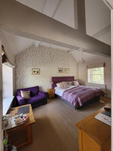 哈廷顿马尼福德旅馆酒店的一间卧室配有一张大床和一张紫色沙发