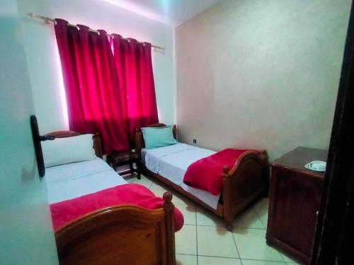 阿加迪尔Entire Apartment的小房间设有两张床,配有红色窗帘