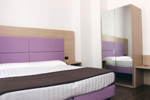 佛罗伦萨埃斯佩兰萨酒店的一间卧室配有一张大床和紫色床头板