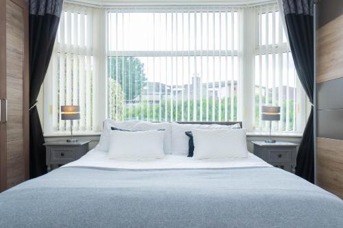 阿伯丁Dwellcome Home Ltd 3 Double Bedroom Semi with Garden and Drive的一张大床,窗户前配有白色枕头