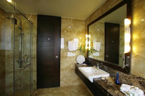 古尔冈古尔冈胡斯塔酒店 的一间带水槽、淋浴和镜子的浴室