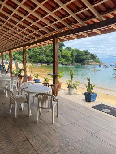 Praia VermelhaPousada Frezza Mergulho的一个带桌椅的庭院,享有海滩美景