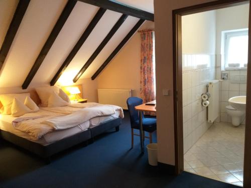 普莱滕贝格Hotel Klinger的一间带一张床和一张书桌的卧室以及一间浴室。