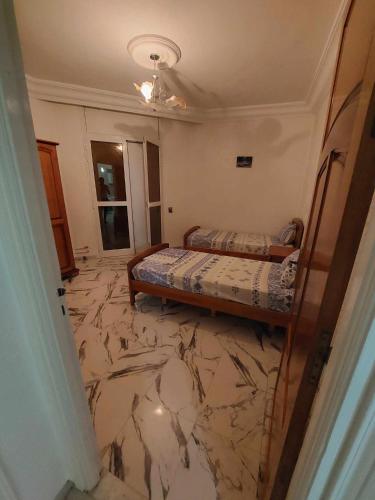 甘达坞伊港Appartement S2 Kantaoui vue mer的一间设有两张床的卧室,铺有大理石地板。