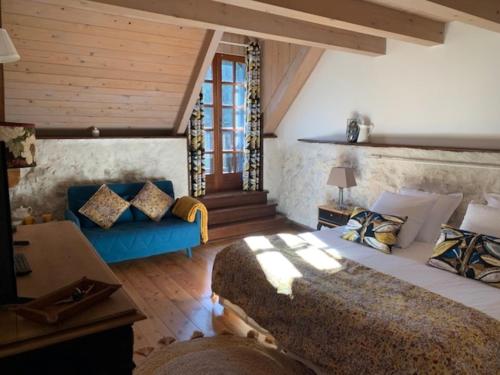 Lepin-le-LacMaison d'hôtes La Bageatière - Lac d'Aiguebelette的一间卧室配有一张大床和一张蓝色的沙发