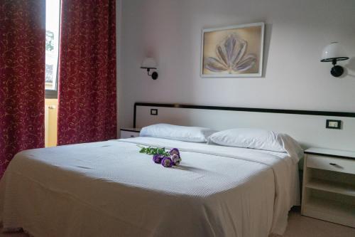 波雷塔泰尔梅Hotel Italia的卧室配有带鲜花的白色床