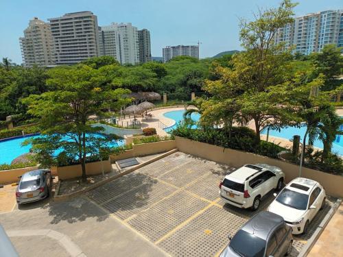 圣玛尔塔Beautiful Beach Apartment in Zazue的停车场,在游泳池旁边停有车辆