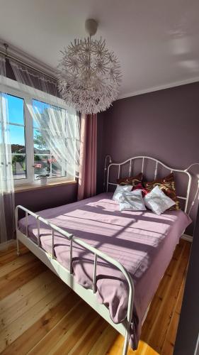 萨拉茨格里瓦Jūrmalas māja的一间卧室配有一张带紫色床单和吊灯的床。