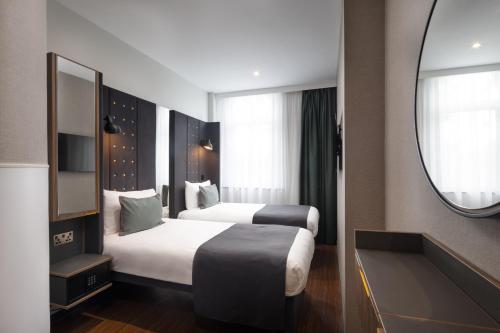 伦敦伦敦国王十字 - 圣潘克拉斯A点酒店 的酒店客房,设有两张床和镜子
