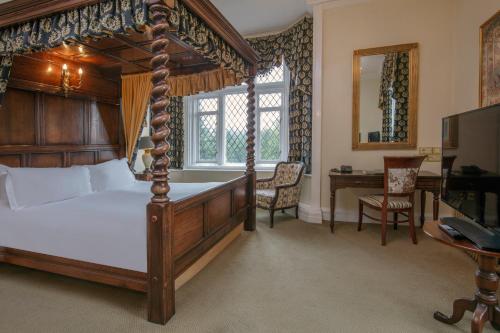 克鲁Crewe Hall Hotel & Spa - Cheshire的一间卧室配有一张天蓬床和一张书桌