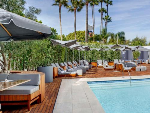 洛杉矶Cameo Beverly Hills的游泳池旁的游泳池配有躺椅和遮阳伞