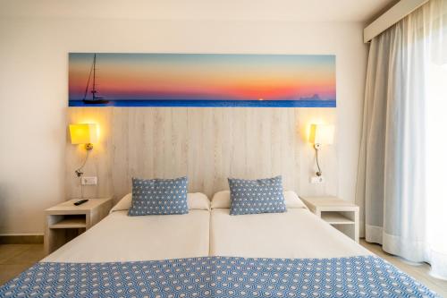 普拉亚登博萨肯博萨俱乐部酒店的卧室配有一张床,墙上挂有绘画作品